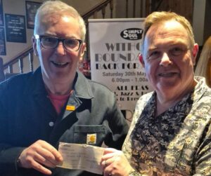 Two men smiling and holding a cheque at Tess Electrical Mechanical event.